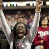 Female student in the crowd at a Temple basketball game has her arms outstretched over her head in glee.