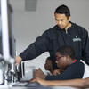 CST student instructs secondary school students on desktop computer. 