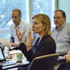 A woman speaking passionately in a classroom while students listen closely.